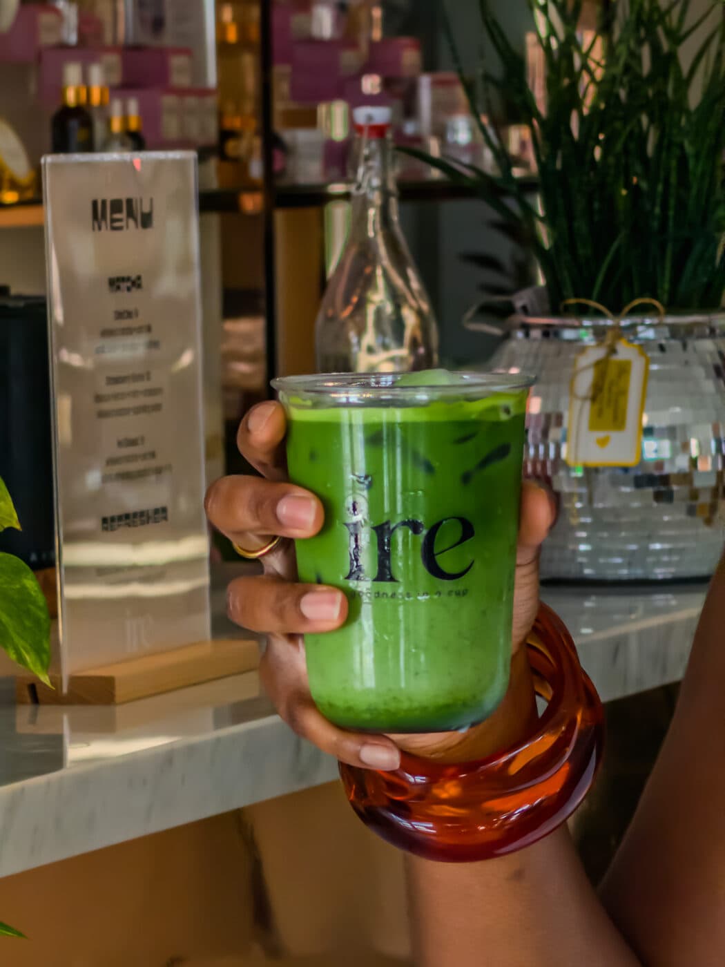 A cup of ire matcha held in hand at the bar